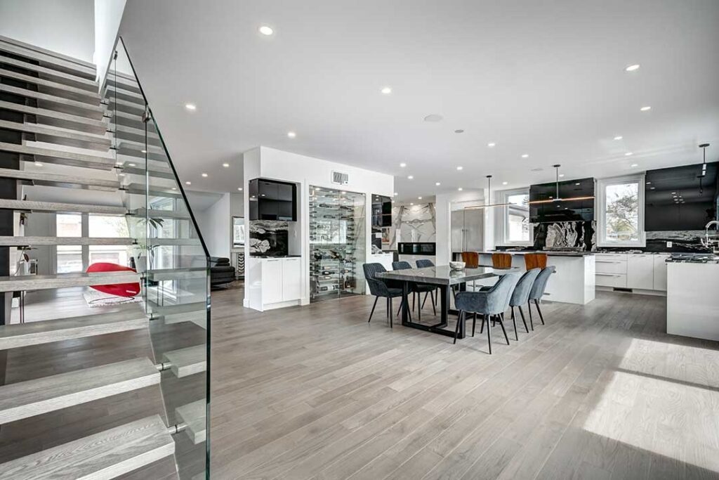 A couple sits at a kitchen table reviewing paperwork and discussing a home purchase contract with pen in hand.