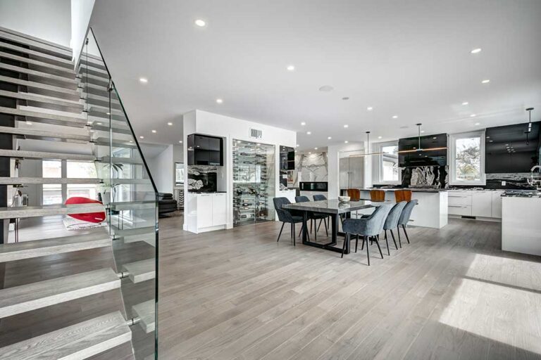 A couple sits at a kitchen table reviewing paperwork and discussing a home purchase contract with pen in hand.