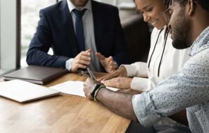 A buyer and agent review property documents at a kitchen table beside a home inspection report.