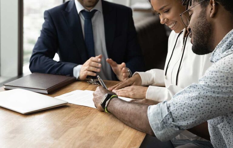 A buyer and agent review property documents at a kitchen table beside a home inspection report.